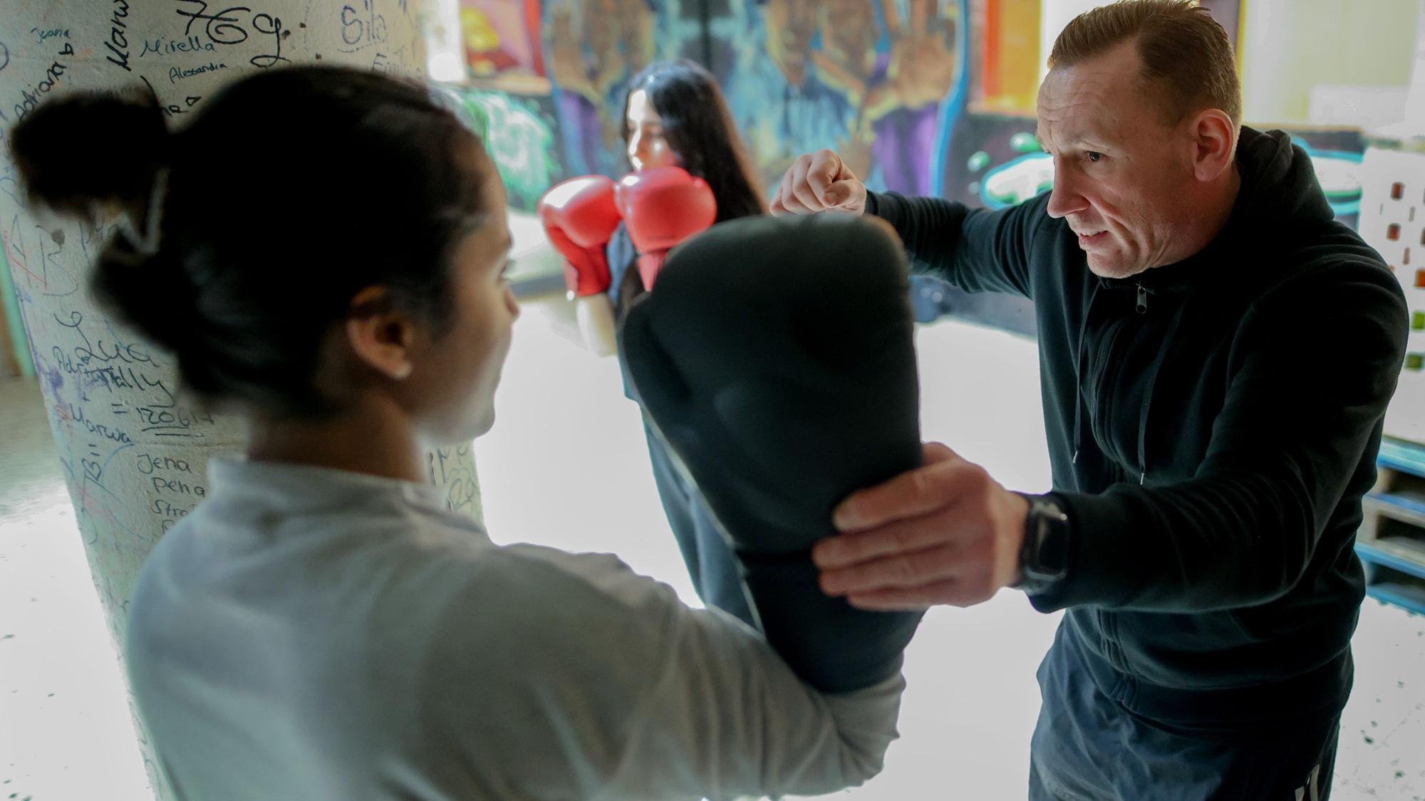 Der ehemalige Boxer René Hehne übt mit einer Schülerin, die Boxhandschuhe trägt.