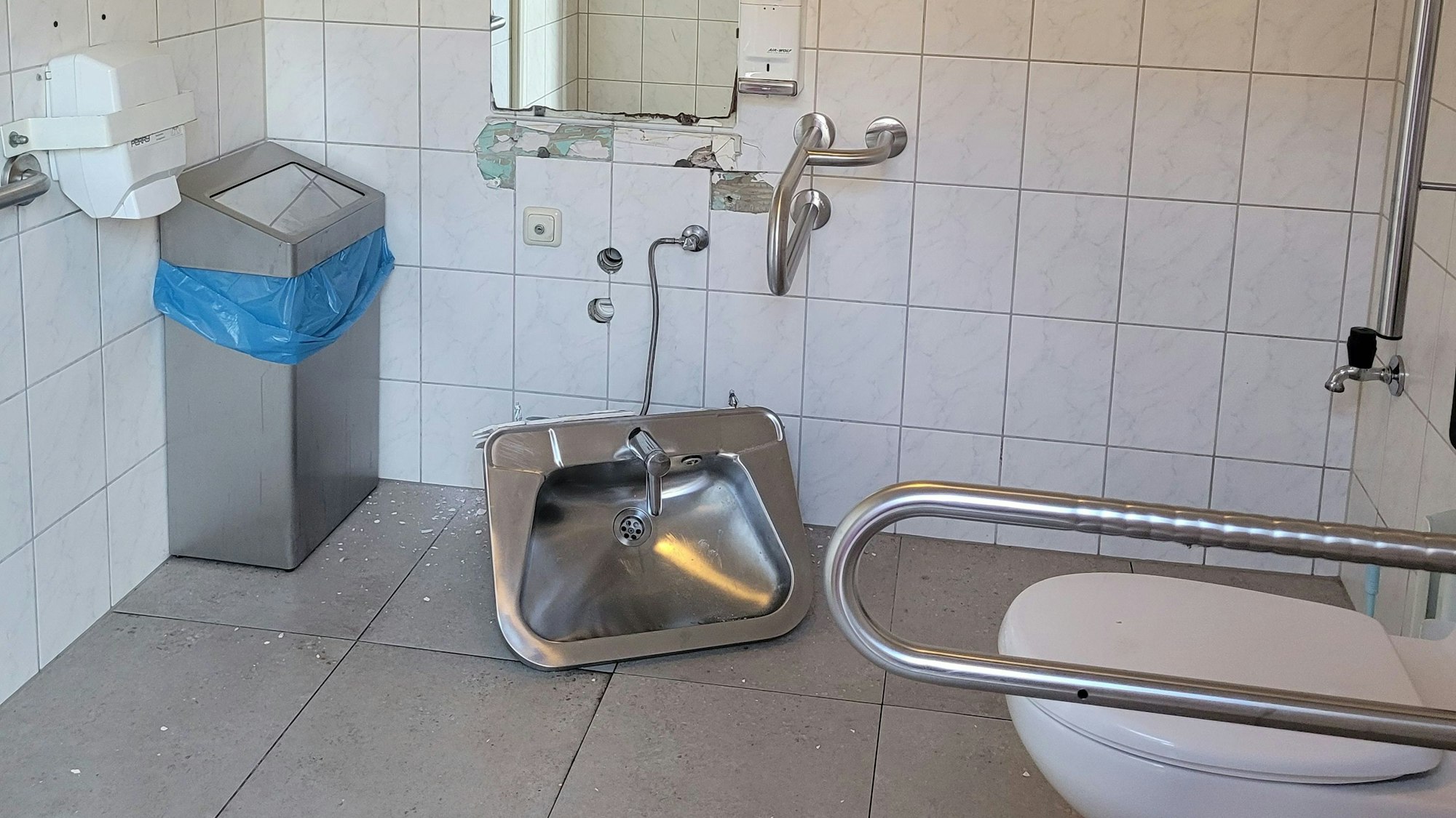 Das Waschbecken wurde mit roher Gewalt von der Wand gerissen und liegt auf den Fliesen.