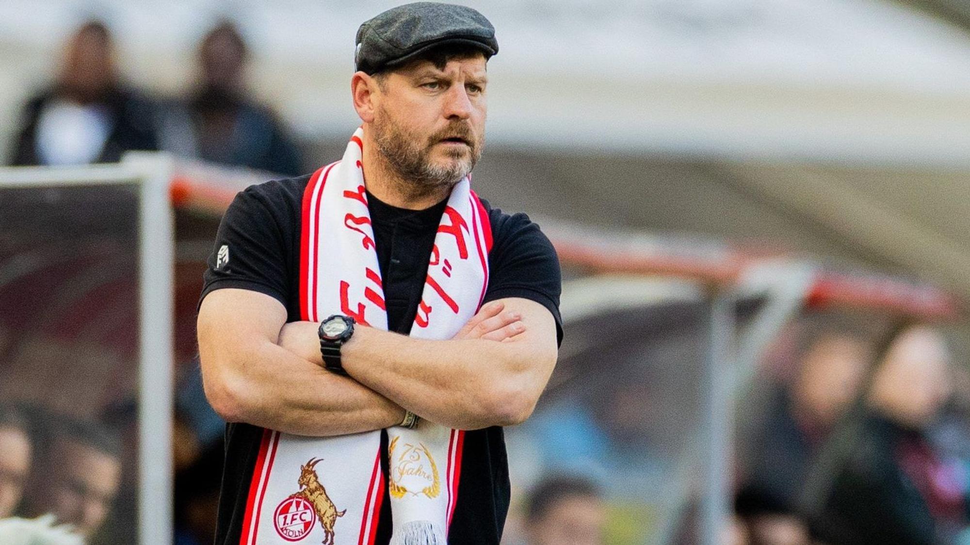 Kölns Trainer Steffen Baumgart trägt einen Jubiläumsschal an der Seitenlinie.