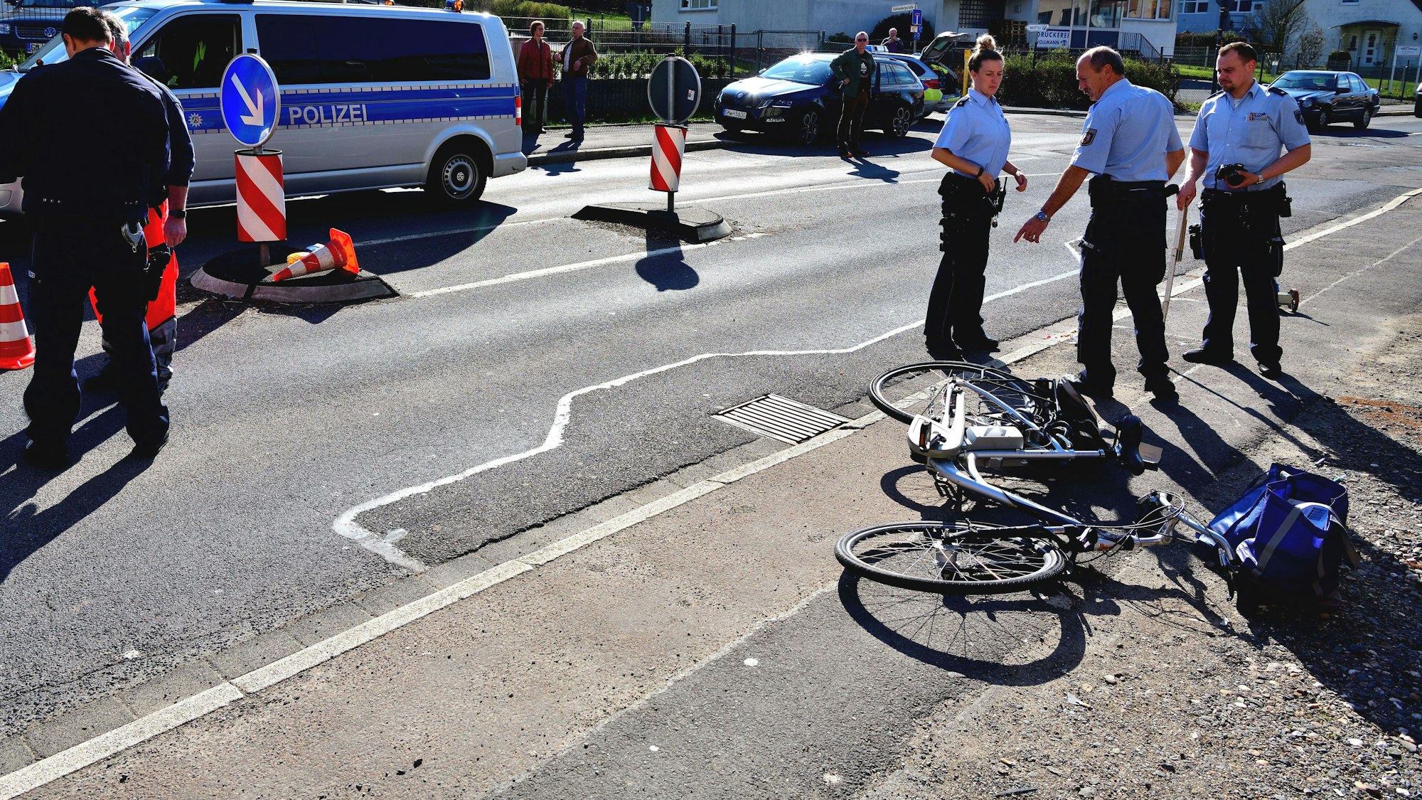 Polizisten stehen auf einer Straße, ein Rad liegt auf dem Boden.