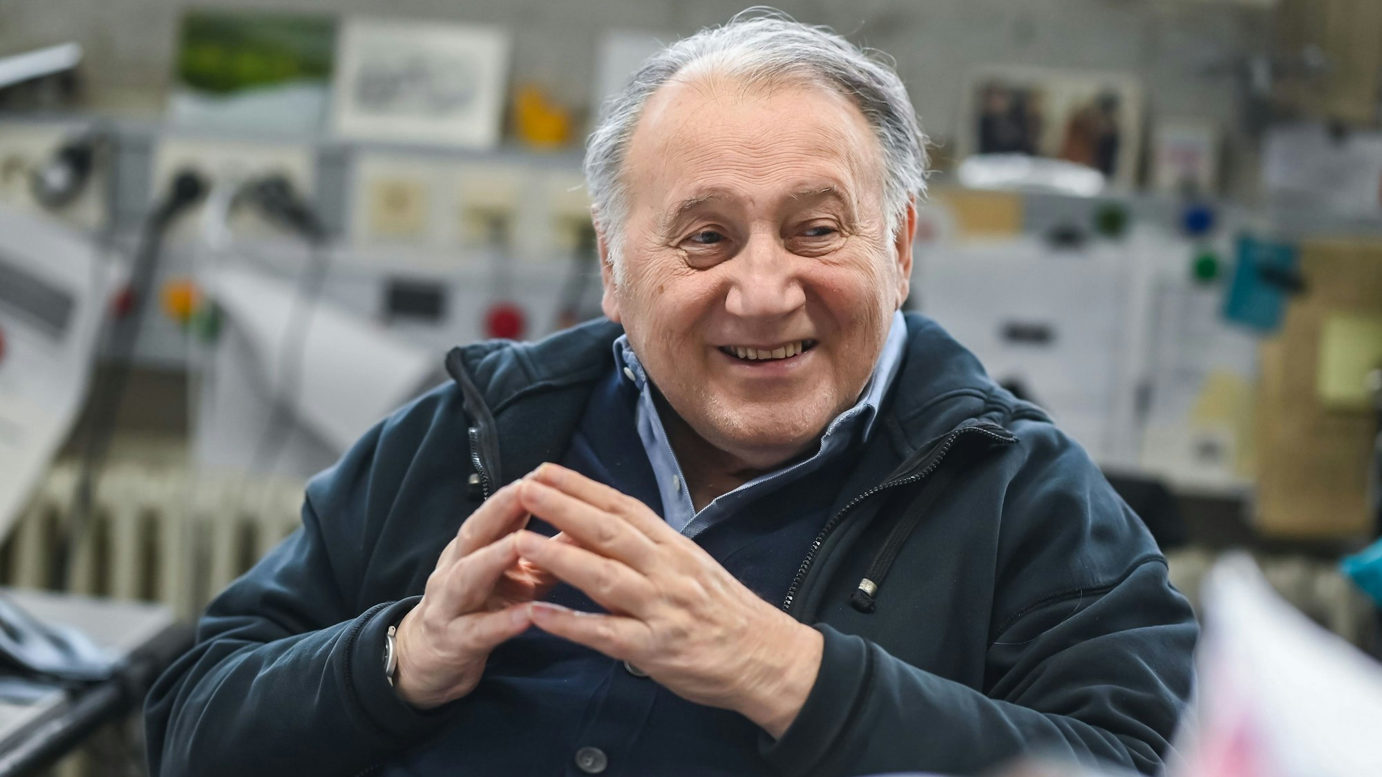 Peter Weibel, Künstler und Direktor des Zentrum für Kunst und Medien (ZKM), sitzt in seinem Büro und lächselt.