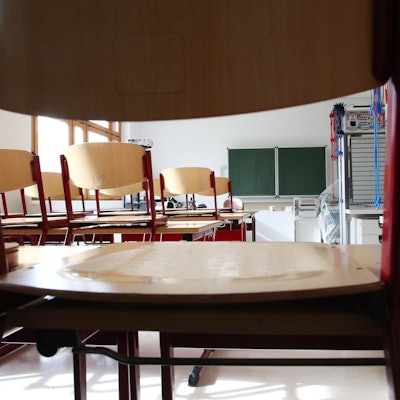 Leere Stühle stehen auf den Pulten einer leeren Klasse.