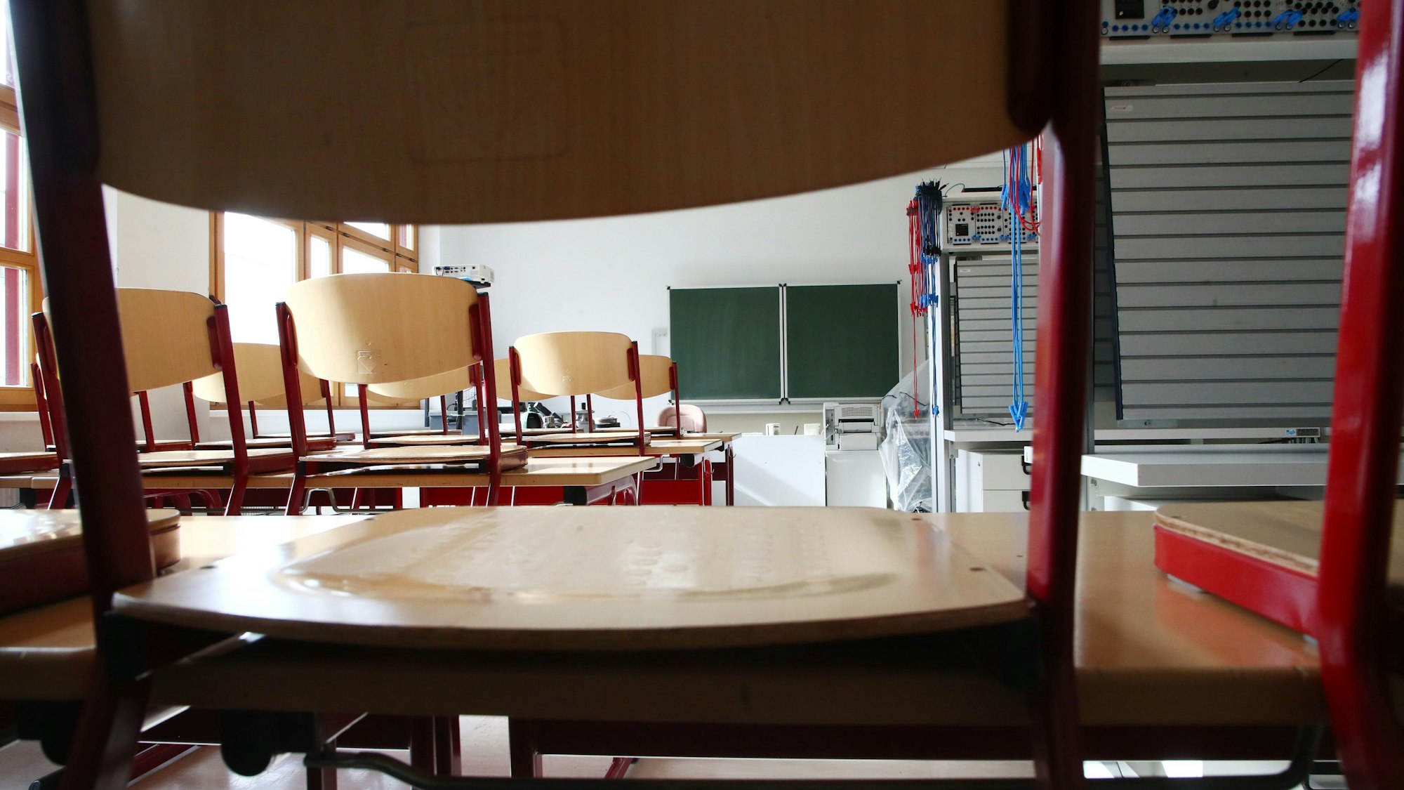 Leere Stühle stehen auf den Pulten einer leeren Klasse.