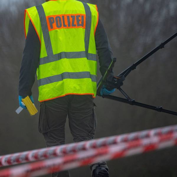 Ein Polizist untersucht einen Tatort. Er trägt eine gelbe Polizei-Weste. (Symbolbild)