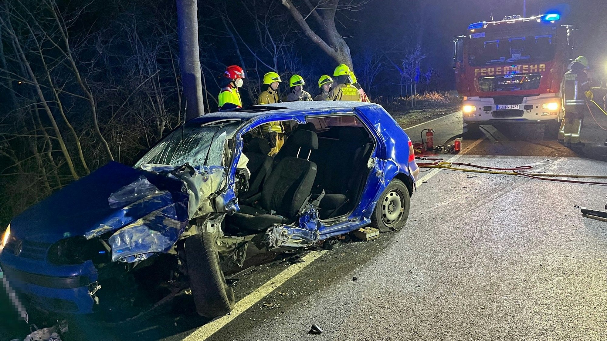 Feuerwehrleute stehen hinter dem Autowrack.