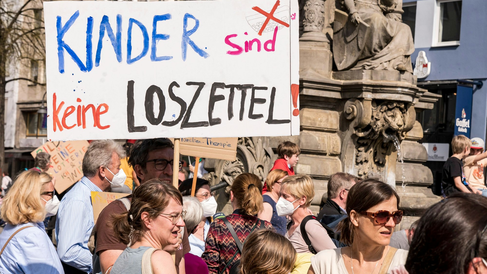 Eltern auf dem Alter Markt. Sie halten Schilder in der Hand, mit denen sie gegen die Verlosung von Schulplätzen demonstrieren.