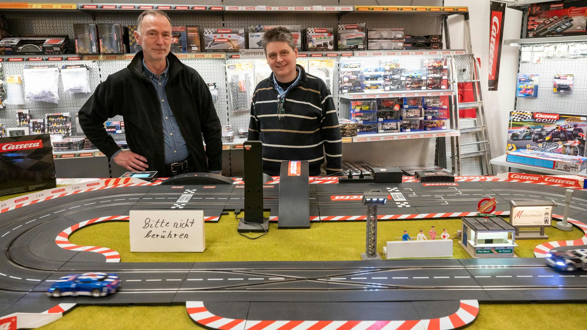 Christian Meerfeld und Lutz Leuow stehen im Laden hinter einer großen Carrerabahn.