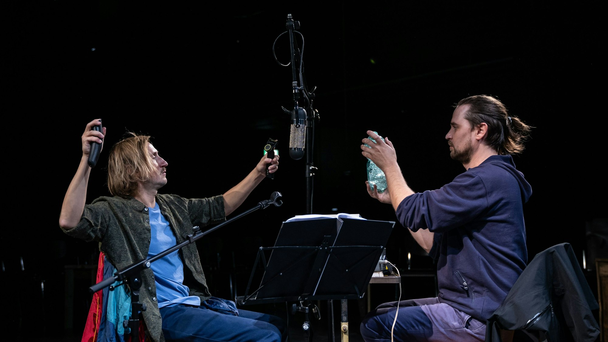 Zwei Männer sitzen vor einem Mikorfon.