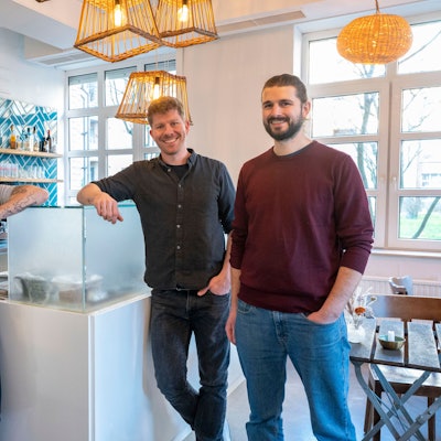 Küchenchef Walter Eckerdt und die Inhaber Helge Holzenburg und Florens Holsten stehen in der Restobar am Tresen.