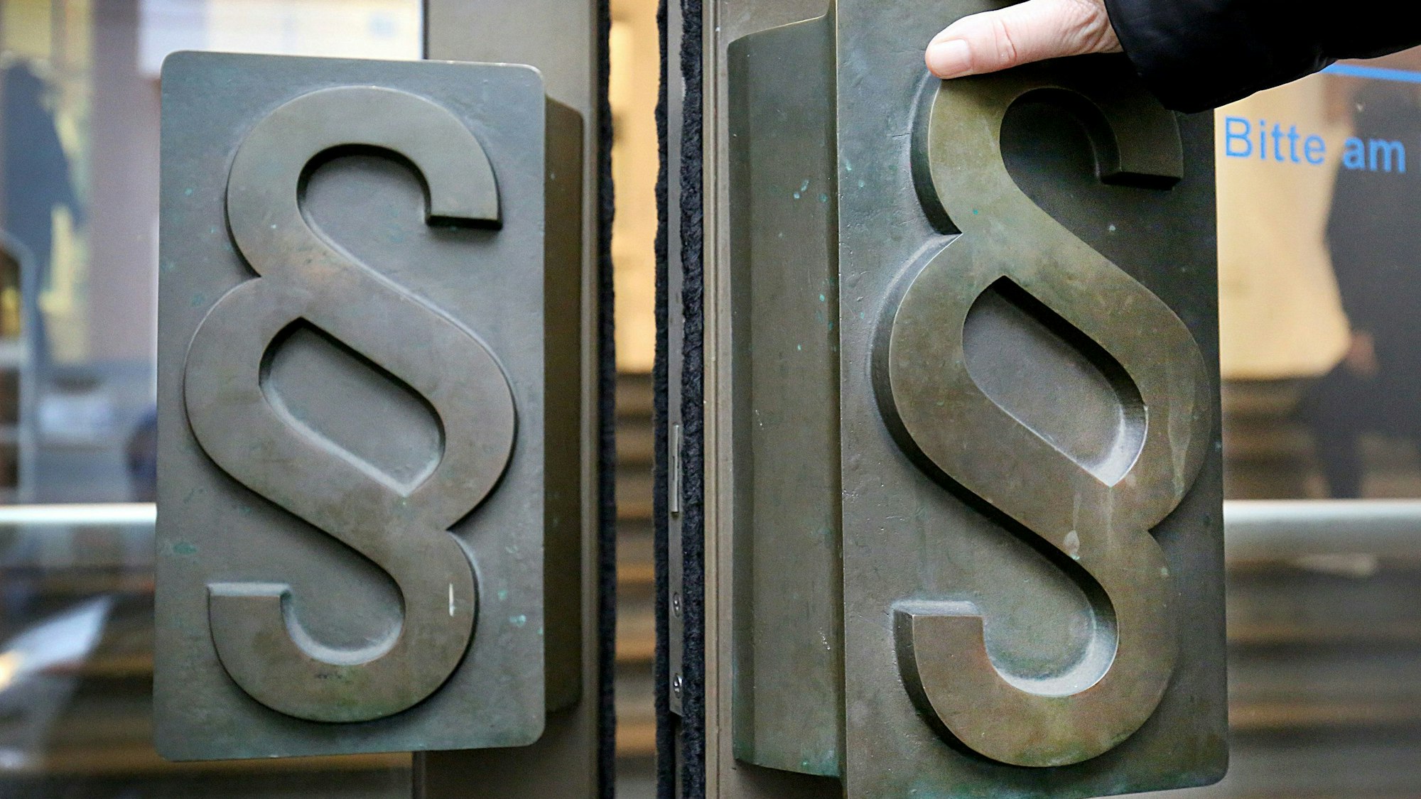 Paragrafen-Symbole sind an Türgriffen am Eingang zum Landgericht Bonn angebracht.