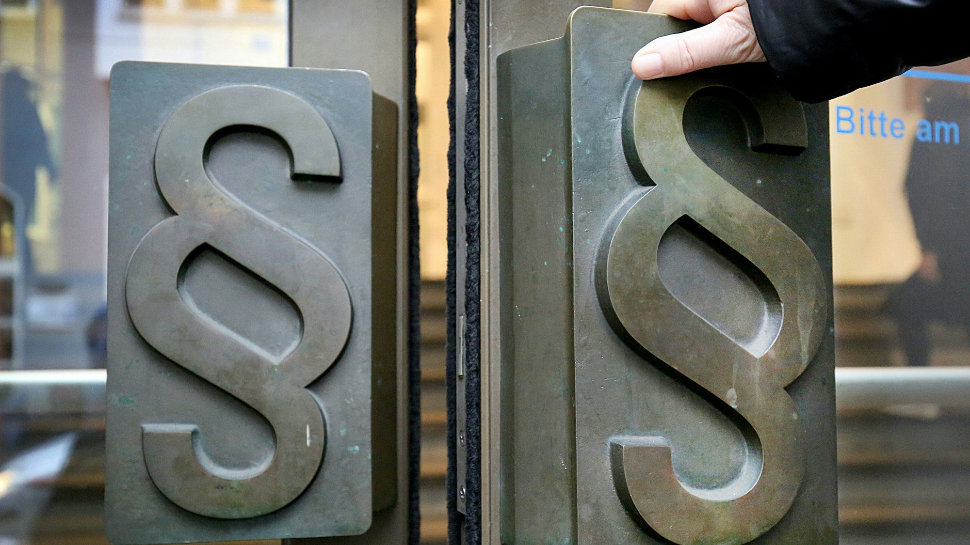 Paragrafen-Symbole sind an den Türgriffen am Eingang zum Bonner Landgericht angebracht.