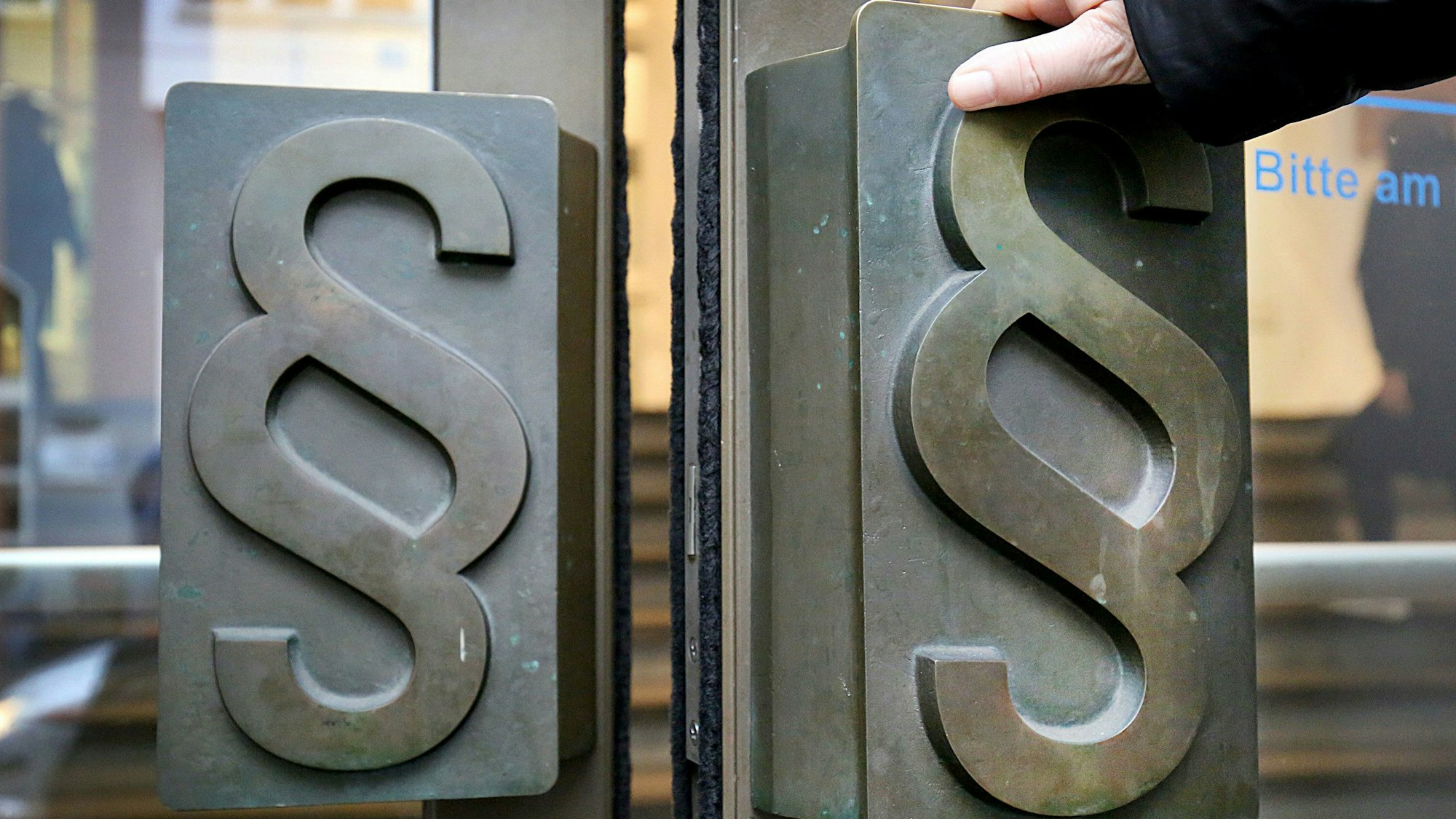 Paragrafen-Symbole sind an Türgriffen am Eingang zum Landgericht in Bonn angebracht.