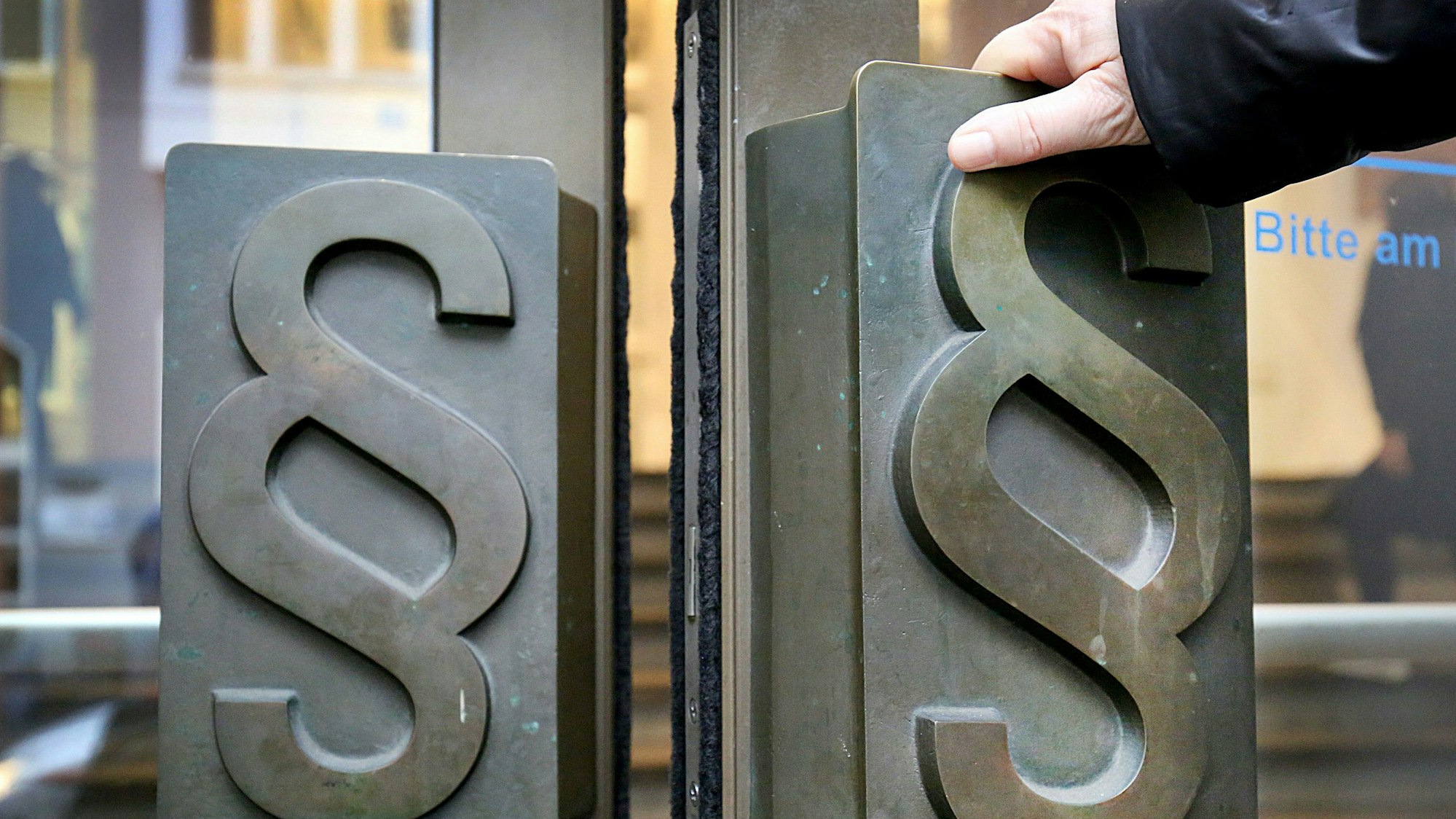 Zwei schwere Eingangstüren; die Griffe tragen das Paragraphenzeichen.