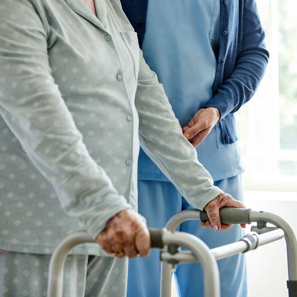 Eine Dame am Rollator mit einer Pflegekraft.