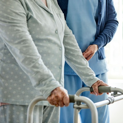 Eine Dame am Rollator mit einer Pflegekraft.