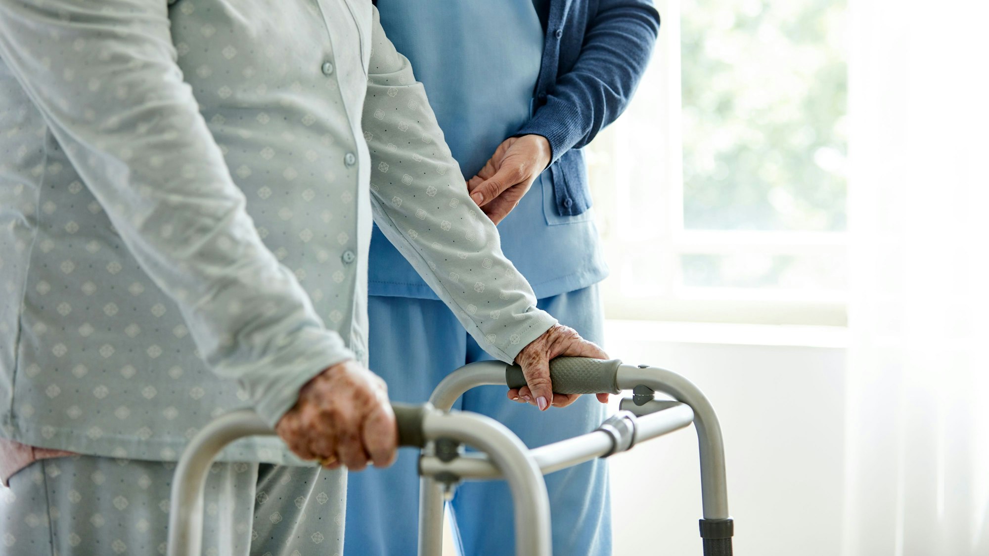 Eine Dame am Rollator mit einer Pflegekraft.