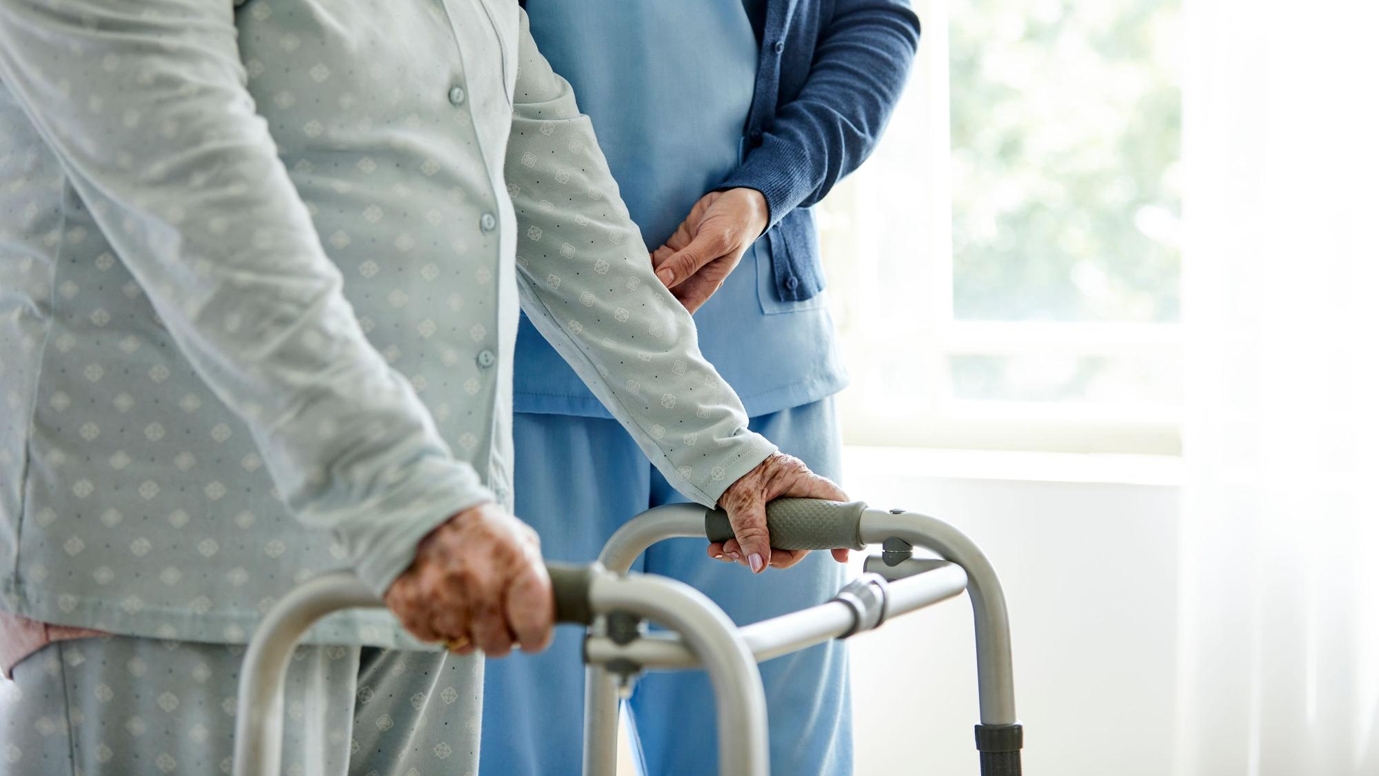 Eine Dame am Rollator mit einer Pflegekraft.