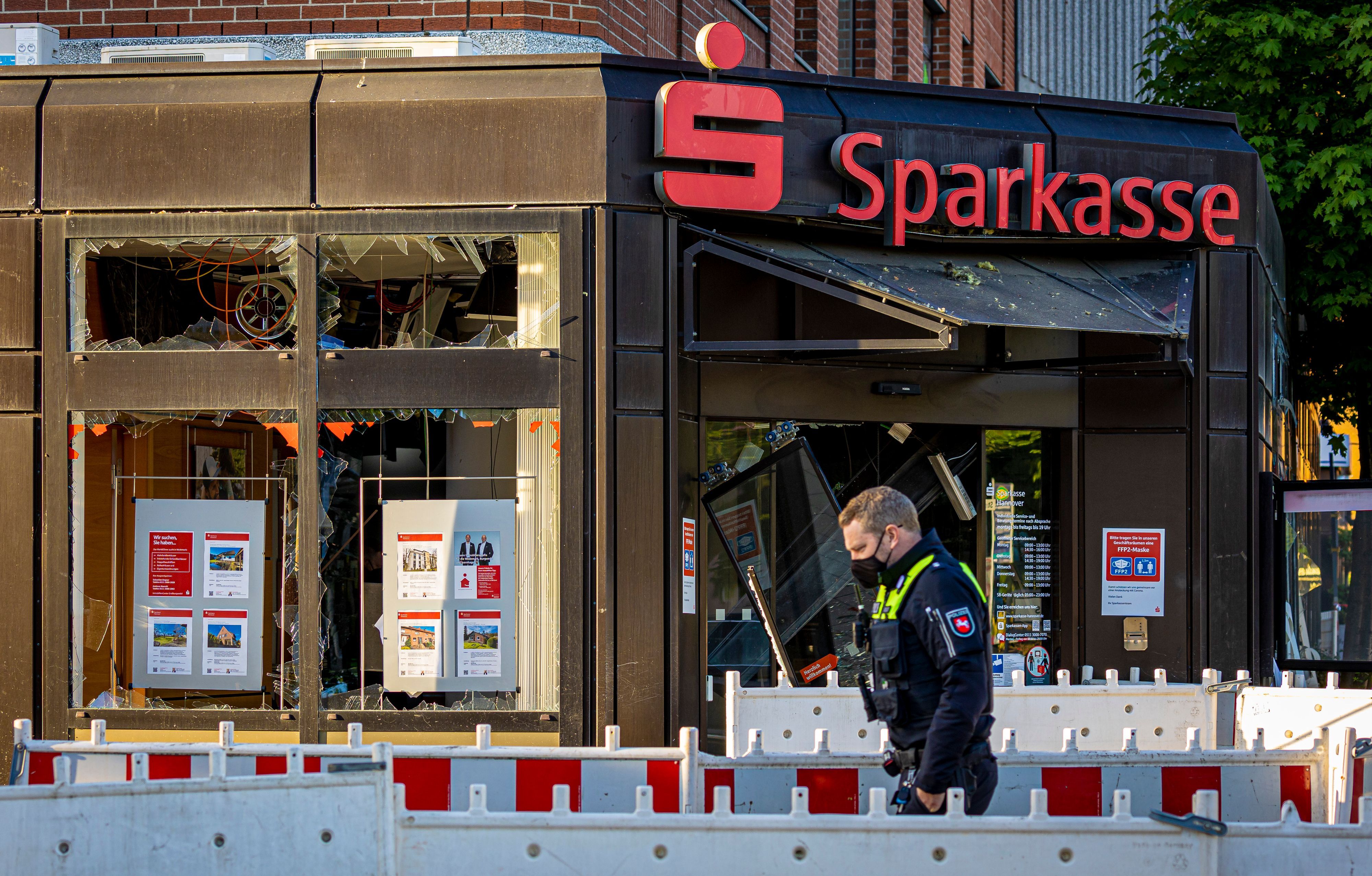 Ein Polizist geht am Morgen vor einer Sparkasse-Filiale entlang, in der es in der Nacht zu einer Geldautomatensprengung kam. (Symbolbild)