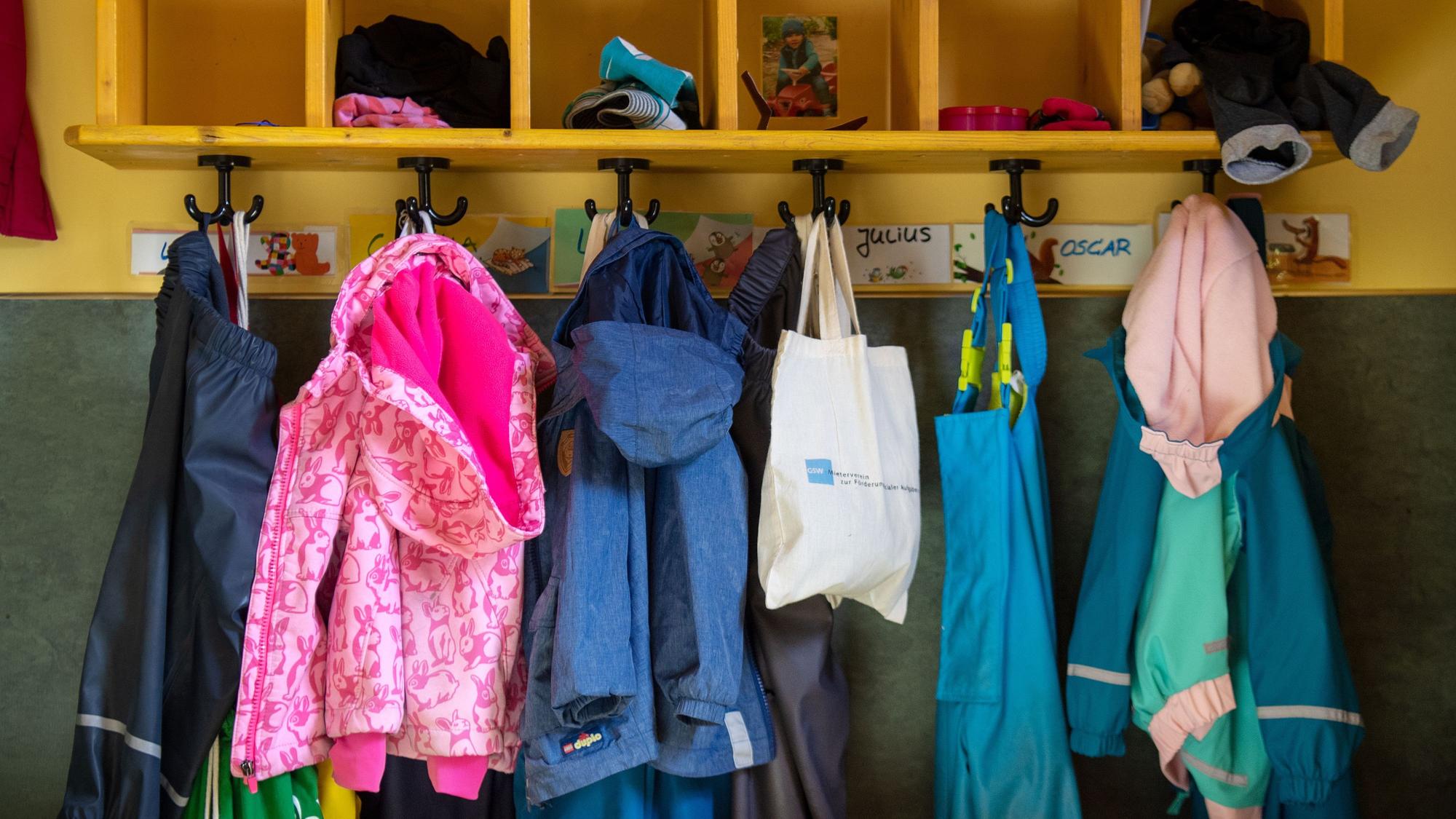Anziehsachen von Kindern hängen an Kleiderhaken.