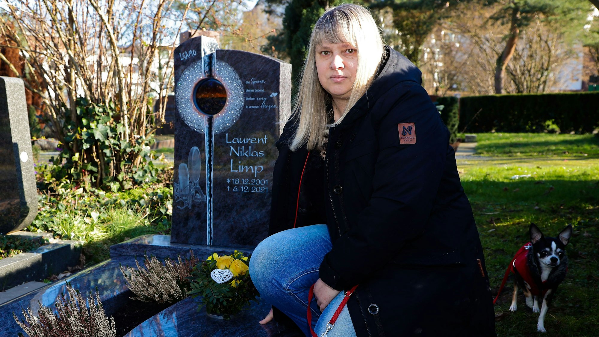 Laurents Mutter mit Hund Emmy am Grab ihres Sohnes Laurent auf dem Friedhof.