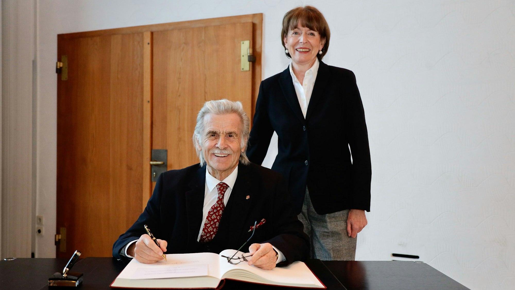 OB Reker steht hinter Helmut Haumann, der sich in das Gästebuch einträgt.