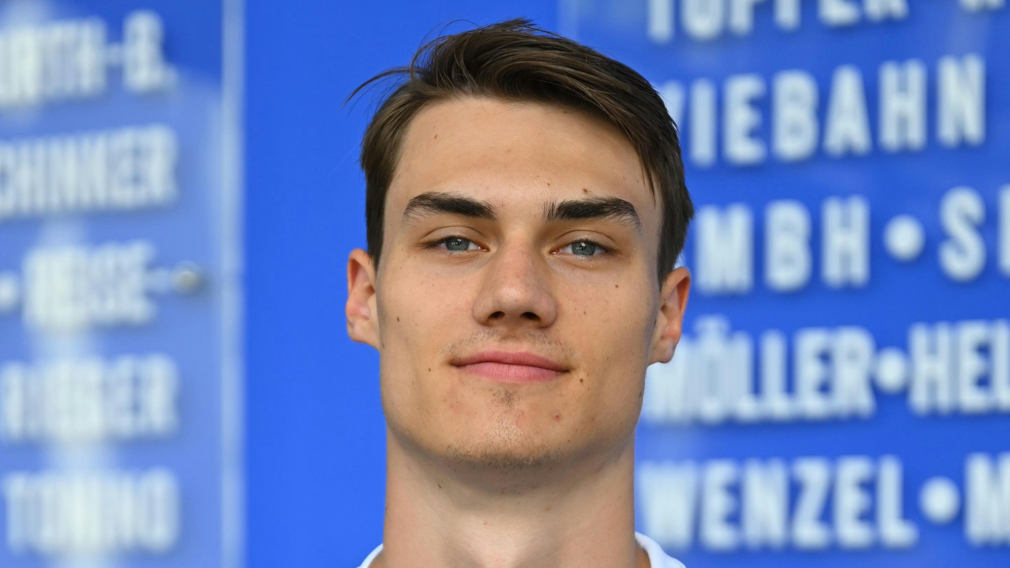 Der Handballer Miro Schluroff ist im Porträt zu sehen. Er trägt ein blau-weißes Trikot des Handballvereins VfL Gummersbach.