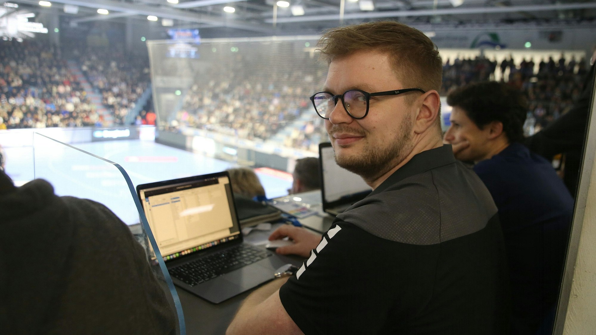 Jan Schwenzfeier sitzt während eines Handballspiels in der Schwalbe-Arena an einem Laptop.
