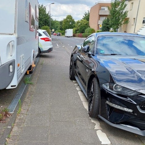 Zugeparkter Gehweg mit extrem schmalem Pfad zwischen Pkw und Wohnwagen.
