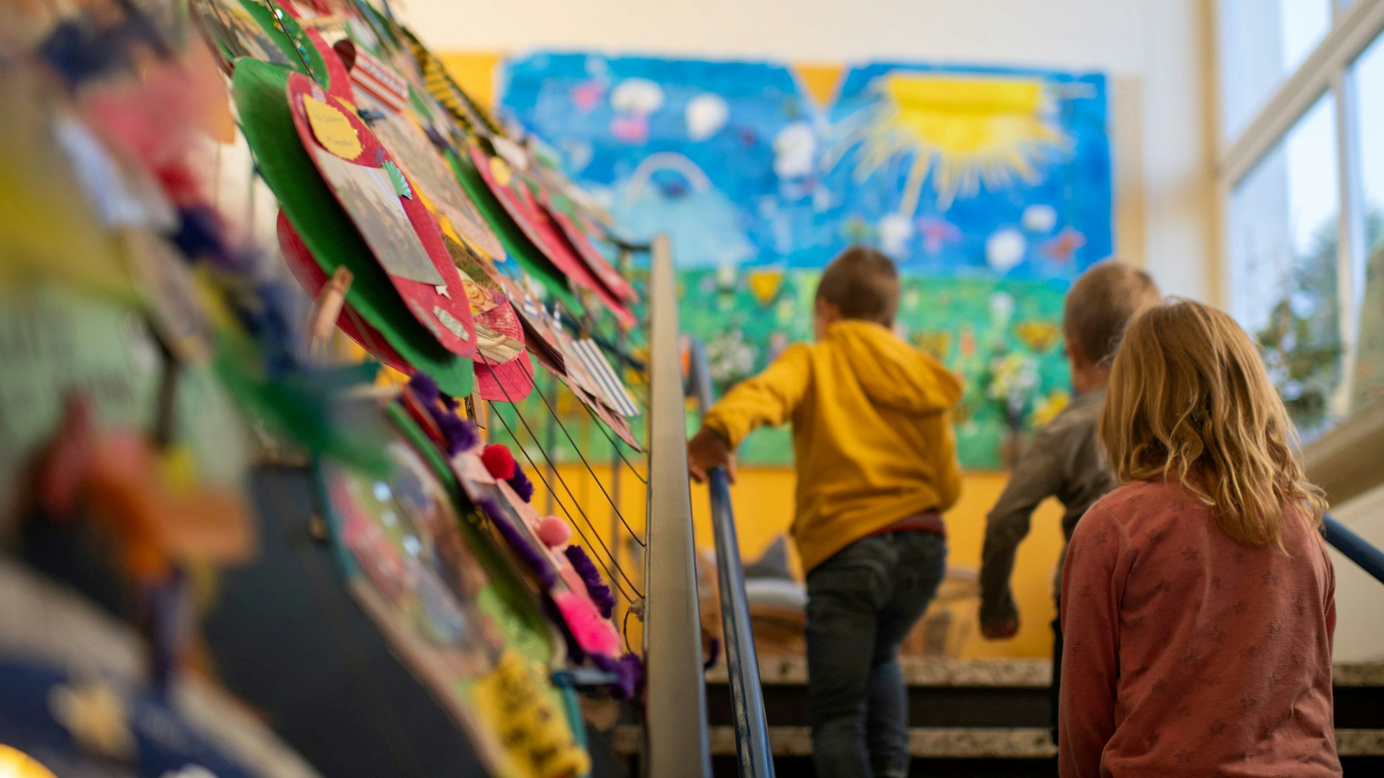 Das Bild zeigt drei Kinder, die eine Treppe in einer Kita hochgehen.