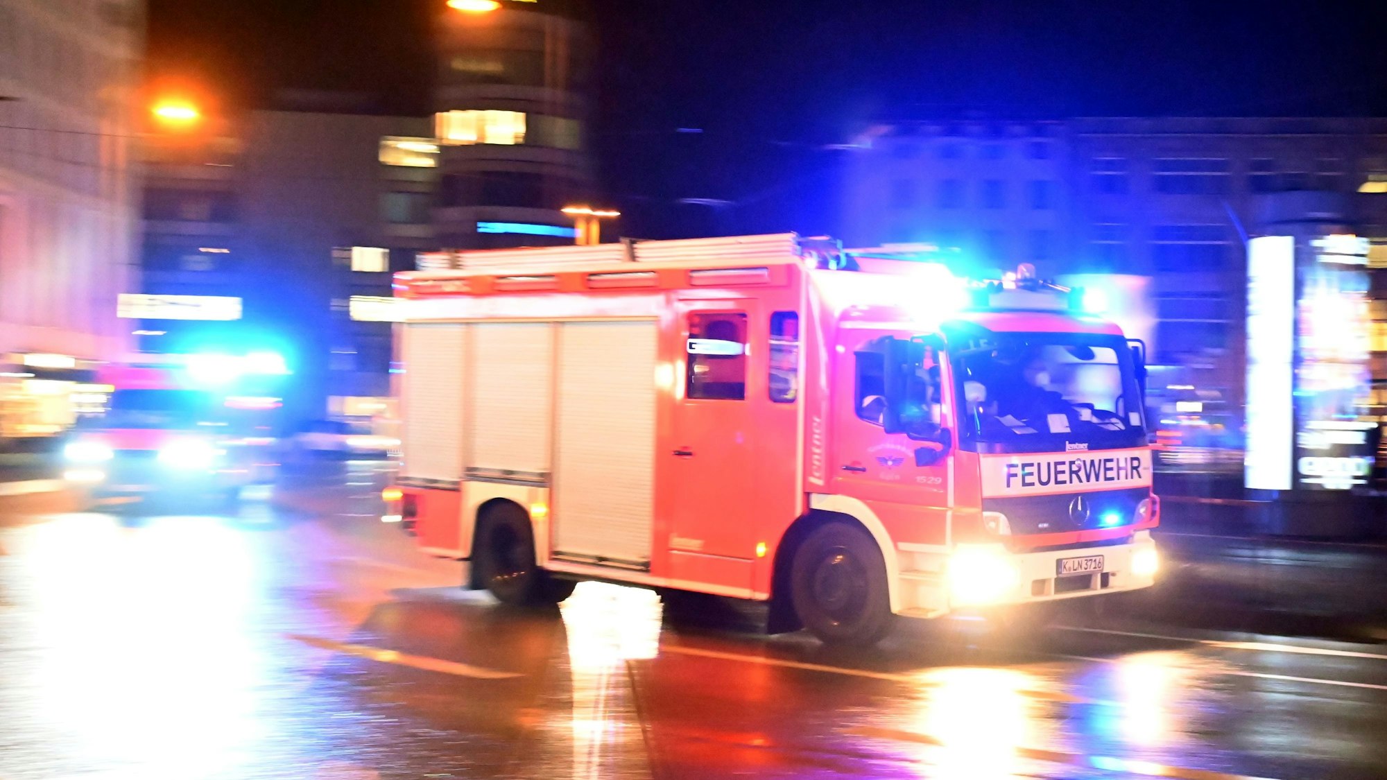 Ein Feuerwehrauto fährt mit Blaulicht über eine Straße bei Nacht.