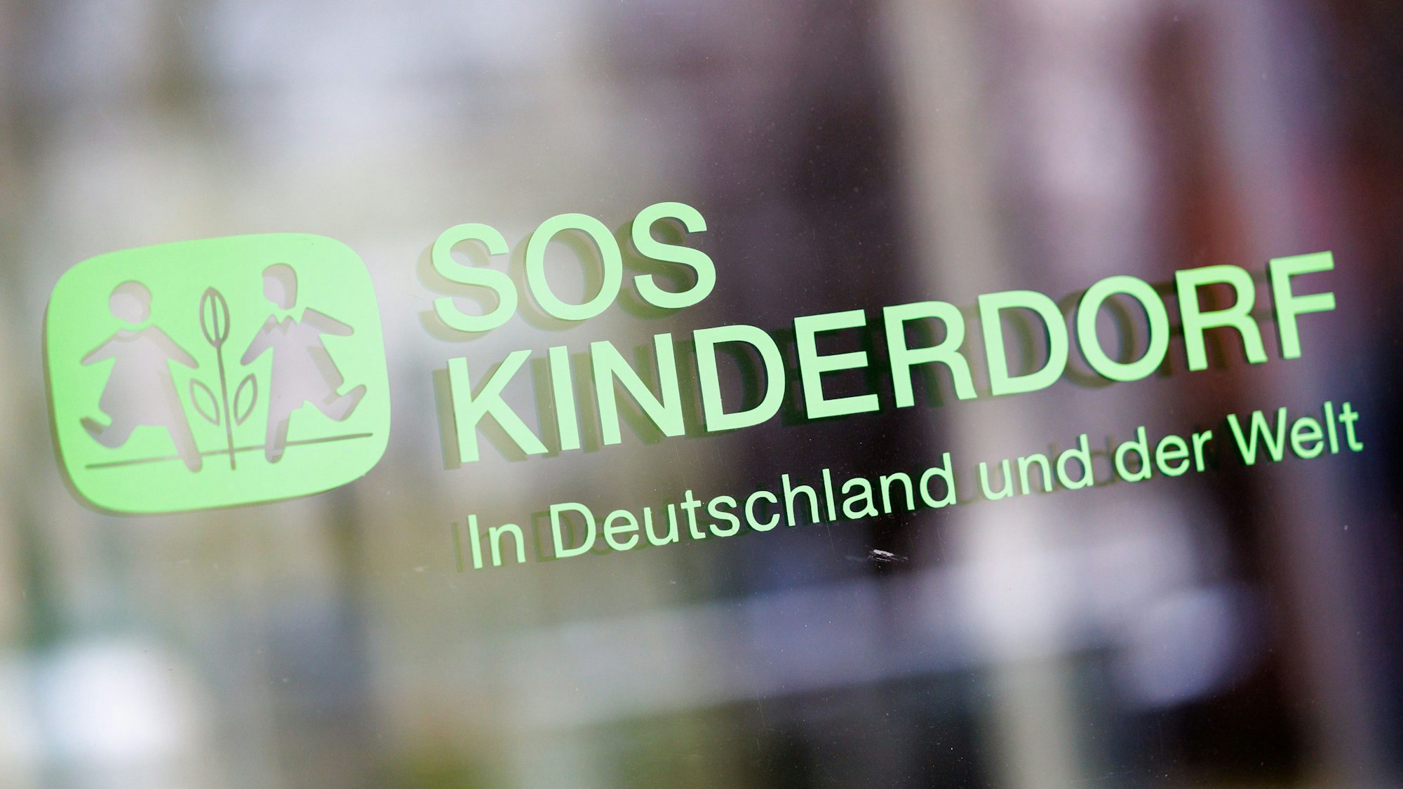 «SOS Kinderdorf – In Deutschland und der Welt» ist an einer Glasscheibe an der Zentrale der Kinderhilfsorganisation SOS-Kinderdorf zu sehen.