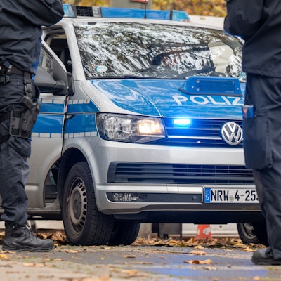 Polizisten stehen vor Einsatzfahrzeugen der Polizei.