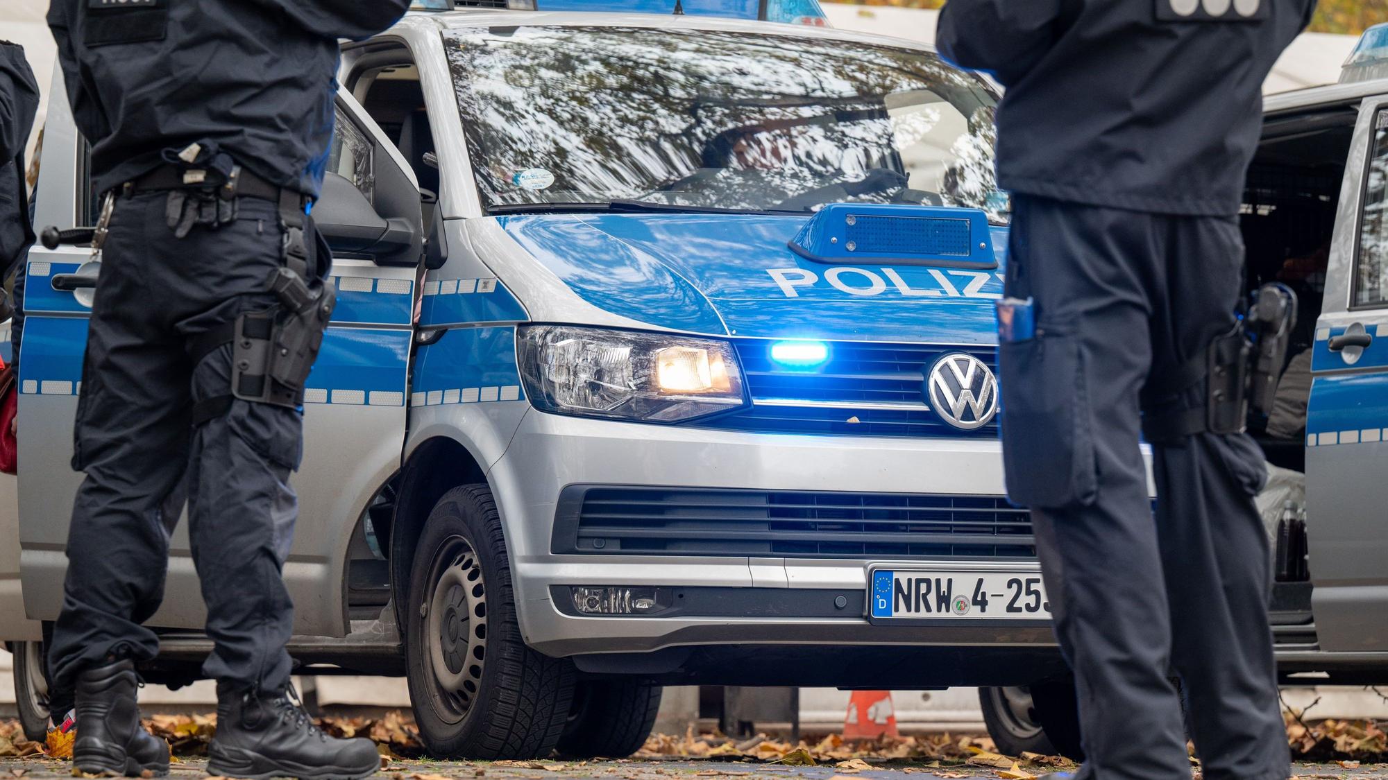 Polizisten stehen vor einem Einsatzfahrzeug.