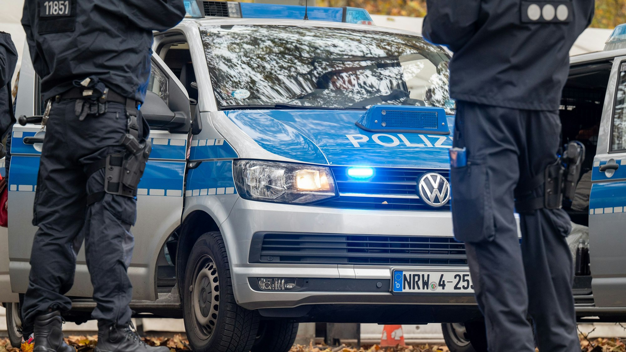Polizisten stehen vor Einsatzfahrzeugen der Polizei.