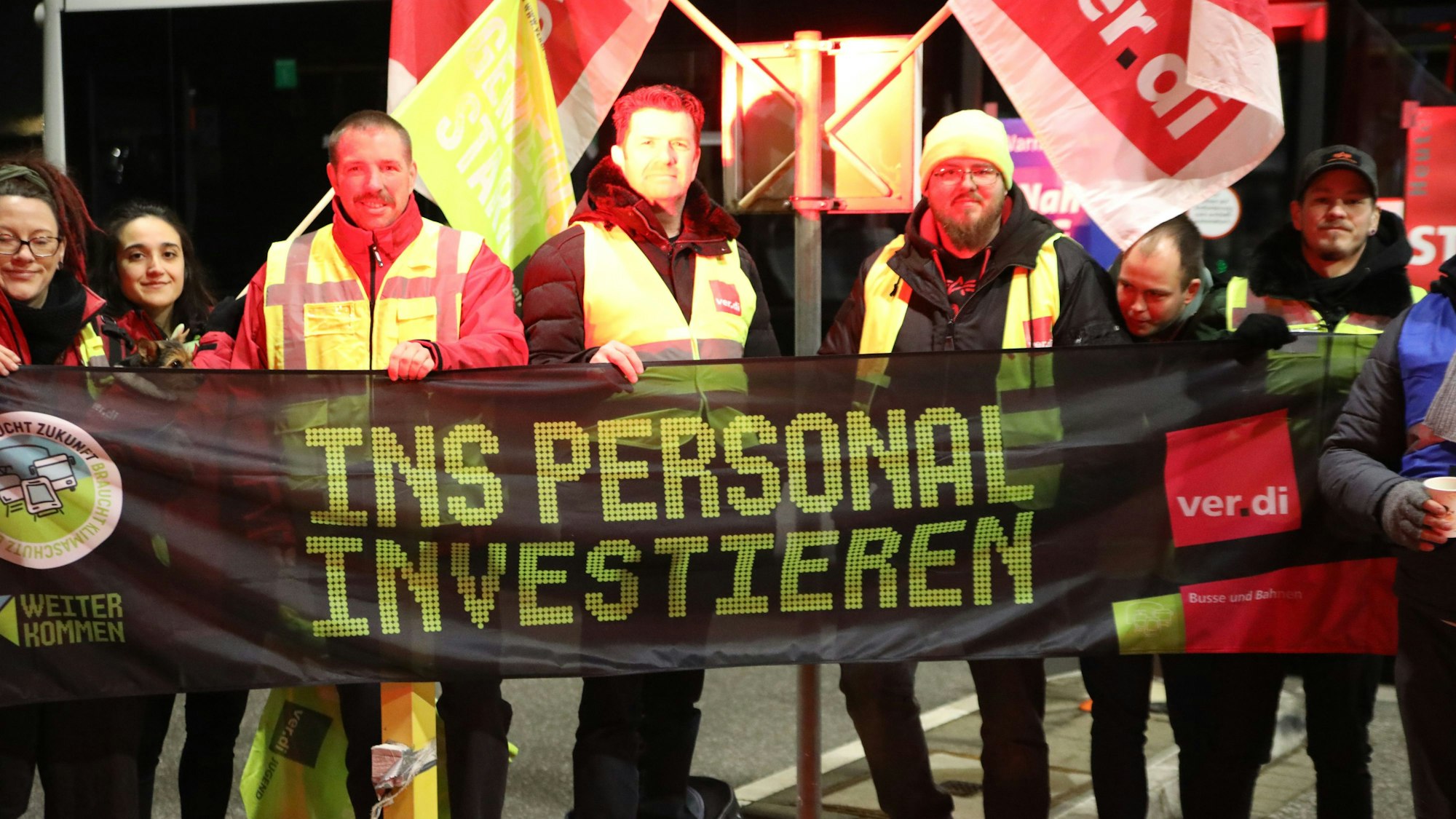 Streikende von Verdi halten am Betriebshof der KVB ein Banner in der Hand.