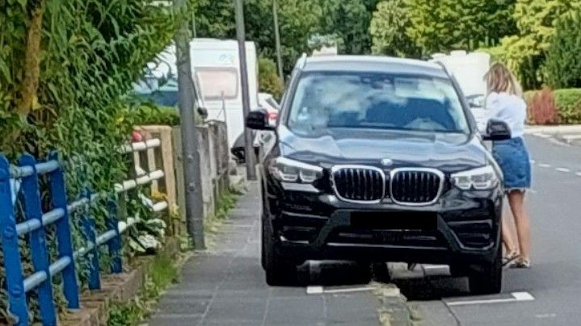 Blick auf einen schwarzen SUV, der den Gehweg versperrt.