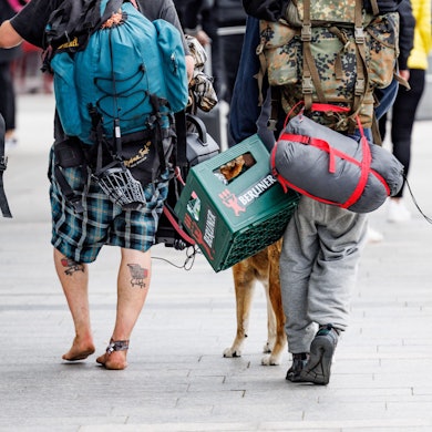 Eine Gruppe Punks schlendert mit Rucksäcken, umgeschnallten Schlafsäcken und einer Kiste Bier in der Hand durch die Fußgängerzone von Westerland auf Sylt.