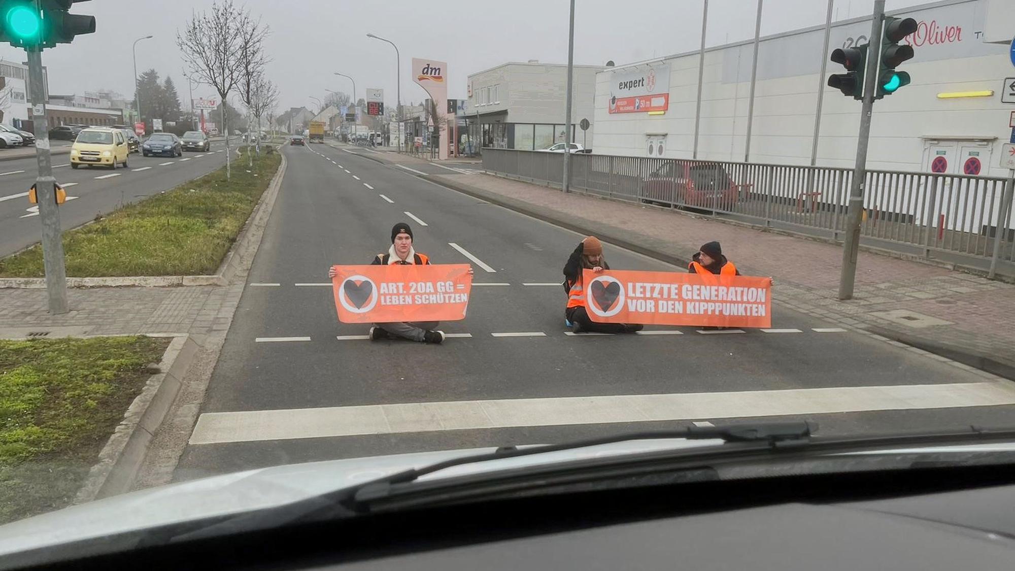 Drei Männer mit Plakaten der Gruppe „Letzte Generation“ wollten sich auf der Roitzheimer Straße in Euskirchen festkleben.