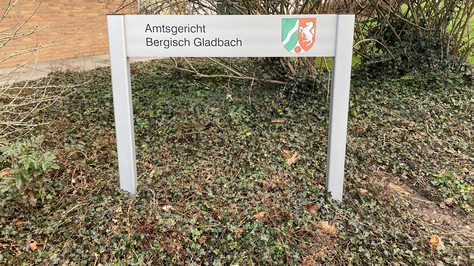 Vor dem Amtsgericht steht ein Schild mit der Aufschrift Amtsgericht Bergisch Gladbach.
