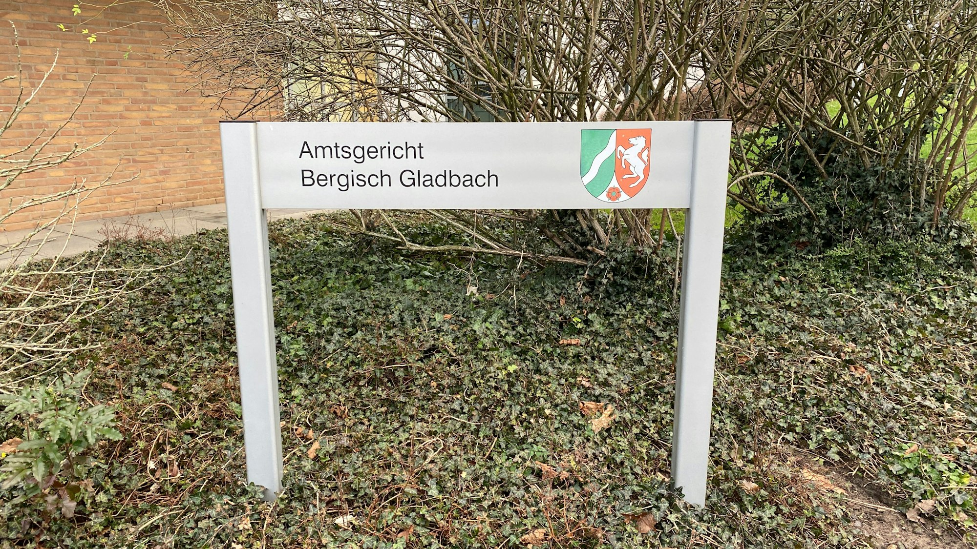 Das Hinweisschild am Bergisch Gladbacher Amtsgericht mit dem farbigen Landeswappen.