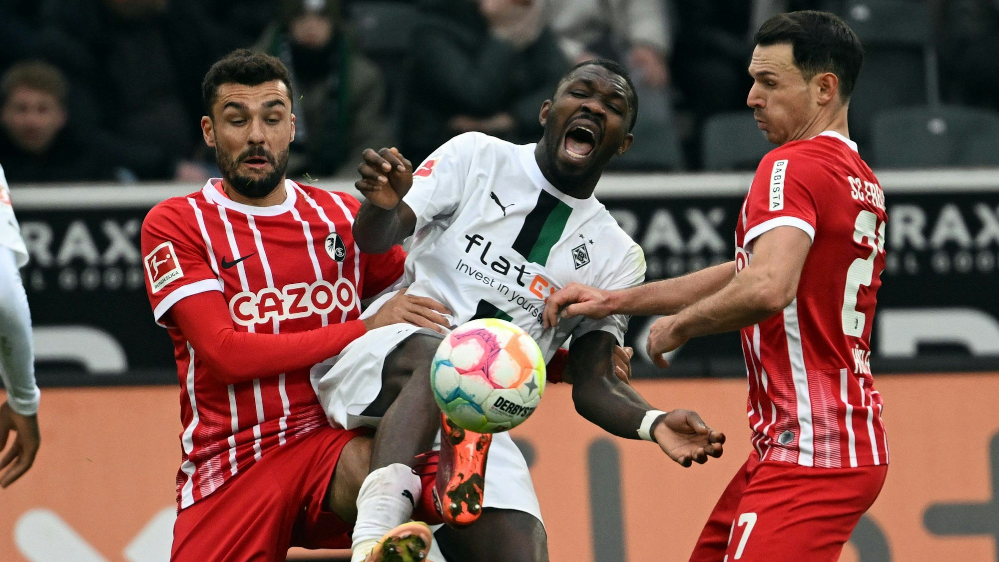 Gladbachs Marcus Thuram (M) und Freiburgs Manuel Gulde (l) und Nicolas Höfler kämpfen um den Ball.