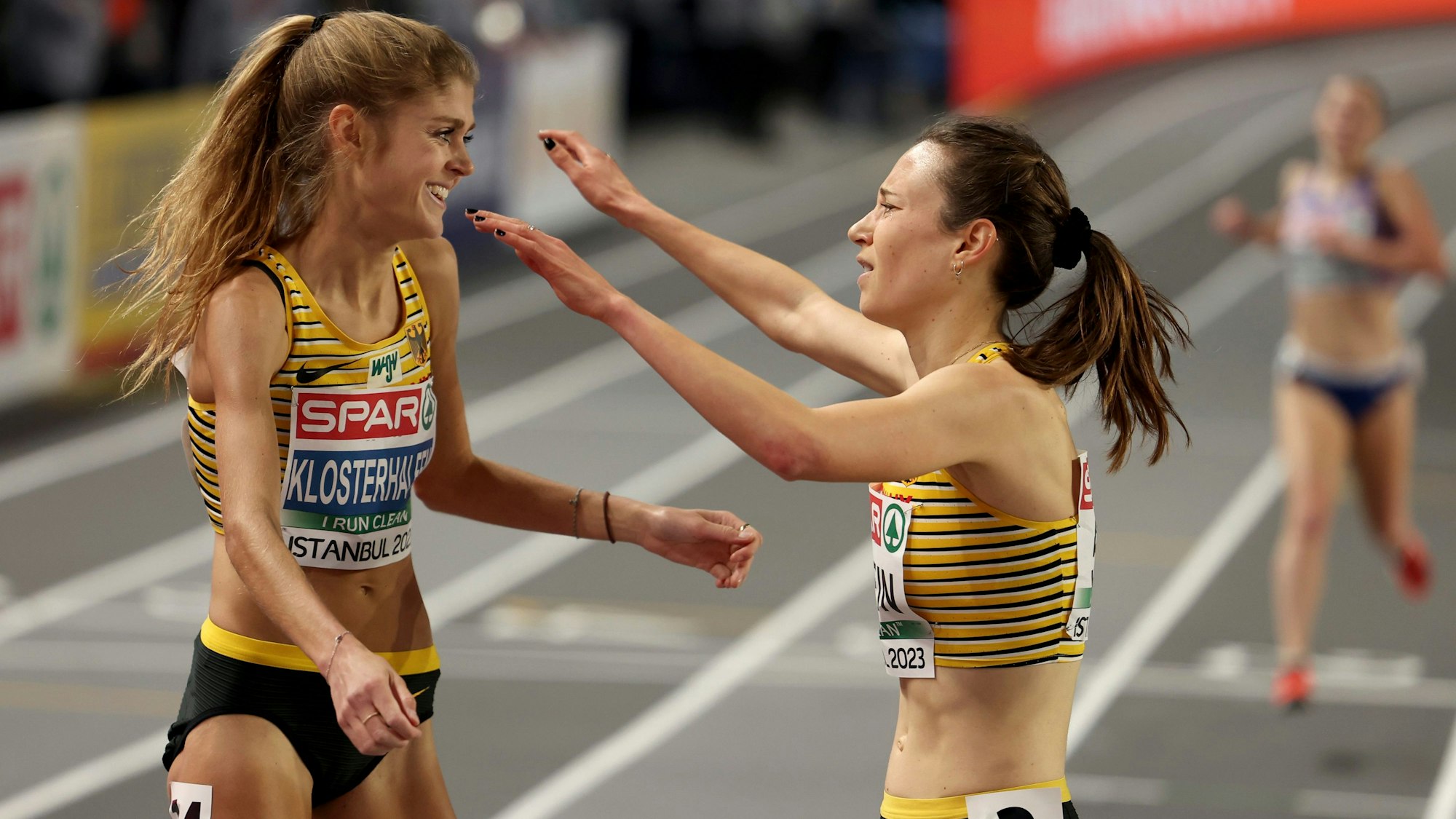 Gold medalist Hanna Klein, center, and silver medalist Konstanze Klosterhalfen, both of Germany, embrace each other after crossing the finish line in the Women 3000 meters final at the European Athletics Indoor Championships at Atakoy Arena in Istanbul, Turkey, Friday, March 3, 2023. (AP Photo)
