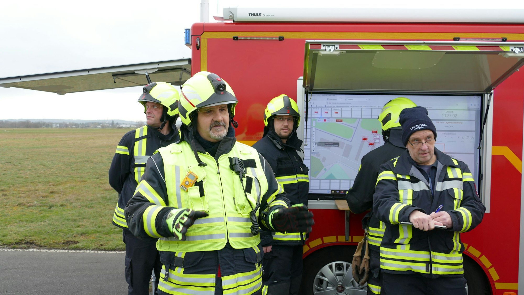 Feuerwehrleute stehen vor dem Bildschirm.