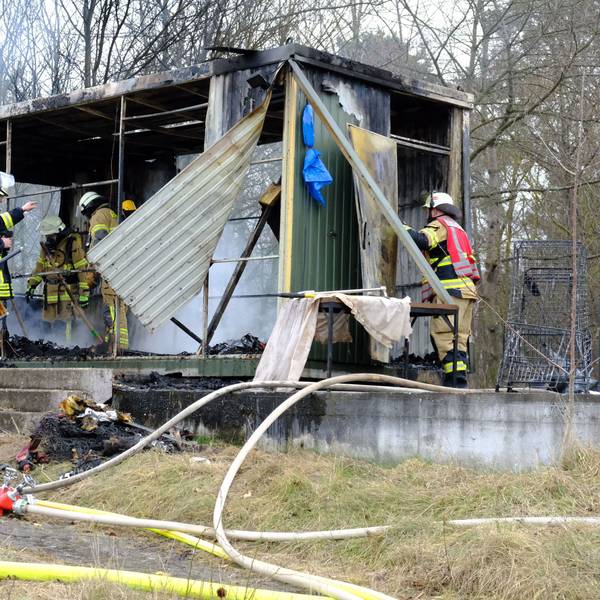 Man sieht Einsatzkräfte, wie sie die letzten Brandherde im Container löschen.