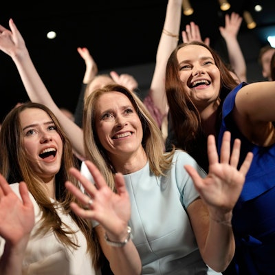 Mitglieder der Reformpartei und Anhänger von Ministerpräsidentin Kaja Kallas posieren für ein Bild. Sie haben die Hände erhoben und lächeln.