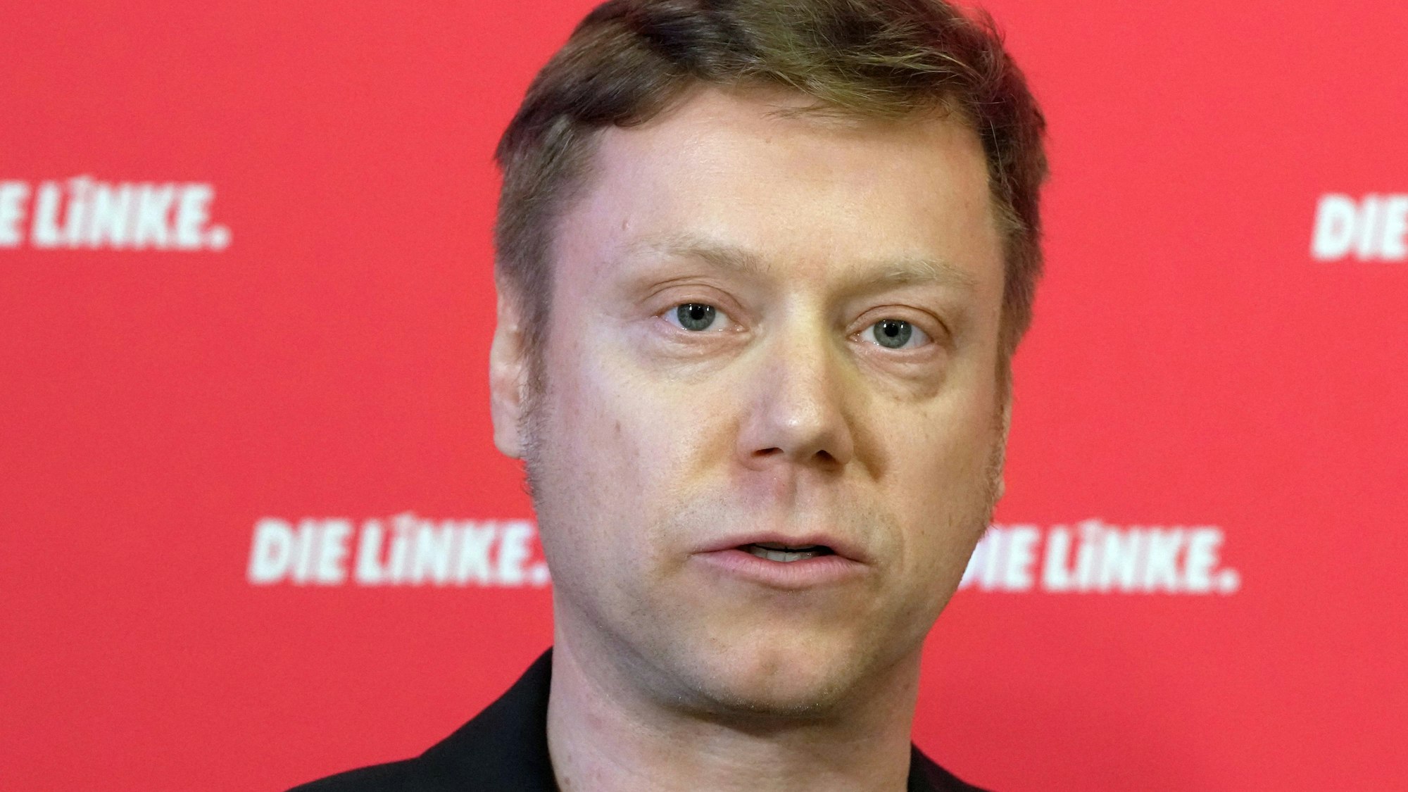 Linken-Chef Martin Schirdewan steht vor einer Werbewand der Linken.