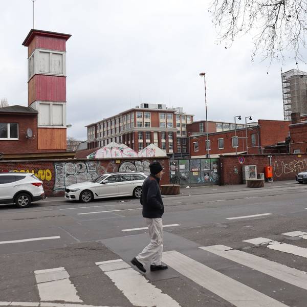 Fußgänger und geparkte Autos vor dem ehemaligen Kölner Güterbahnhof.