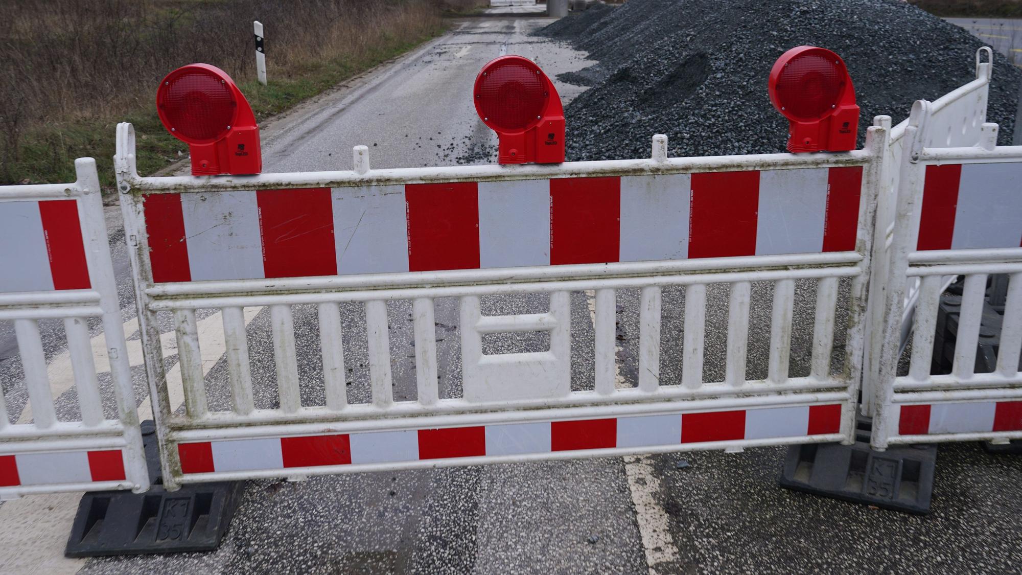 Ein Baustellenzaun versperrt die Durchfahrt einer Straße.