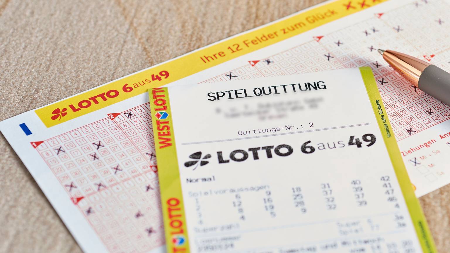 Ein Lotto 6aus49 Tippschein und ein Los liegen auf dem Tisch.