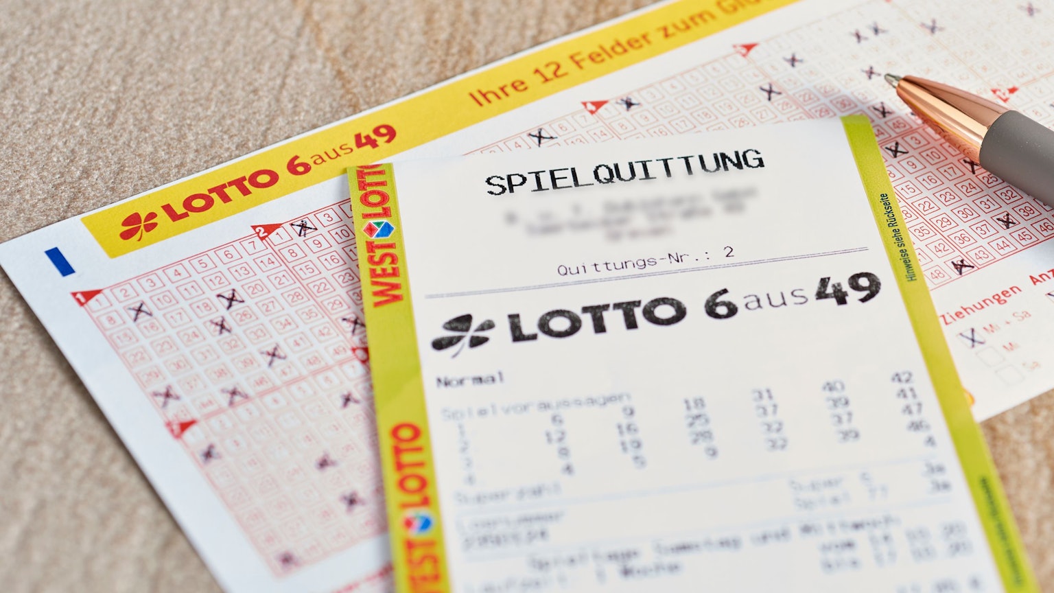 Ein Lotto 6aus49 Tippschein und ein Los liegen auf dem Tisch.